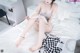 A woman sitting on a bed with her legs crossed.