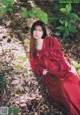 A woman in a red dress sitting on the ground.