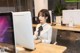 A woman sitting at a desk in front of a computer.