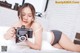 A woman laying on a bed holding a camera.