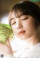 A woman holding a head of cabbage in her hands.