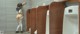 A woman standing in front of a row of urinals in a public restroom.