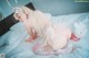 A woman in a pink lingerie sitting on a bed with a teddy bear.